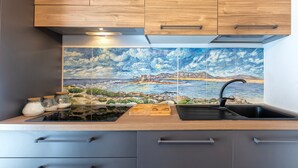 A kitchen with wooden cabinets, a tiled backsplash, a sink, and a countertop with jars and a cutting board. - Holiday Home 'Jacuzzi' with Sea View, Wi-Fi and Air Conditioning (Stintino)