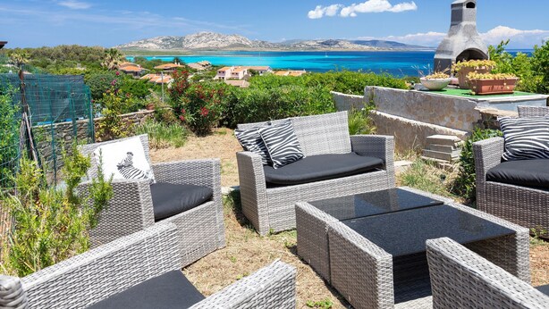 Wicker furniture with cushions, a stone oven, and a view of the sea. - Holiday Home 'Jacuzzi' with Sea View, Wi-Fi and Air Conditioning (Stintino)