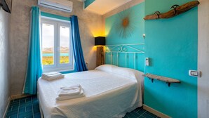 A bedroom with a bed, a window with curtains, a wall-mounted shelf, and a wall decoration. - Holiday Home 'Asinara' with Sea View, Wi-Fi and Air Conditioning (Stintino)