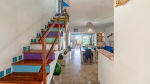 A staircase with colorful steps, a dining area with a table and chairs, and a view through a doorway. - Holiday Home 'Asinara' with Sea View, Wi-Fi and Air Conditioning (Stintino)