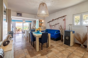 Amplia sala de estar con una mesa de comedor, sofá azul y una lámpara colgante grande.