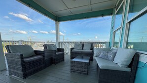 A covered outdoor seating area with wicker furniture and a view of the water. - Coastal View: Beach/Fishing/ Coastal Realty Group (Grand Isle)