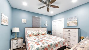 A bedroom with a bed, a nightstand, a dresser, a ceiling fan, and a door. - Coastal View: Beach/Fishing/ Coastal Realty Group (Grand Isle)