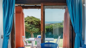 A room with a sliding glass door, a table, and chairs. - Villa 'Alba Piscina Vista Mare' with Sea View, Wi-Fi and Air Conditioning (Stintino)