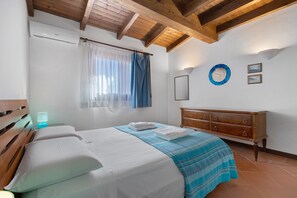 Une chambre à coucher avec un lit, une commode en bois, un miroir et une fenêtre avec des rideaux.