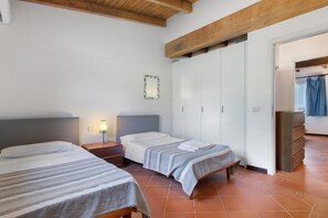 A bedroom with two beds, a wardrobe, and a nightstand.