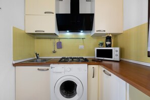 A compact kitchen with a washing machine, a microwave, and a gas stove.