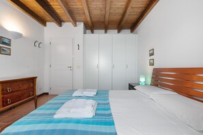 A bedroom with a bed, a wooden headboard, a nightstand with a lamp, a dresser, and a wardrobe.