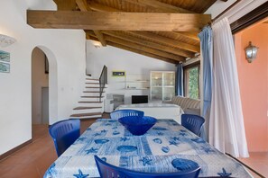 Ein Essbereich mit einem Tisch für zwei Personen, einer Treppe und einer Küche im Hintergrund.