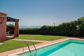 Ein Pool mit Meerblick, ein überdachter Bereich und ein gepflegter Rasen.