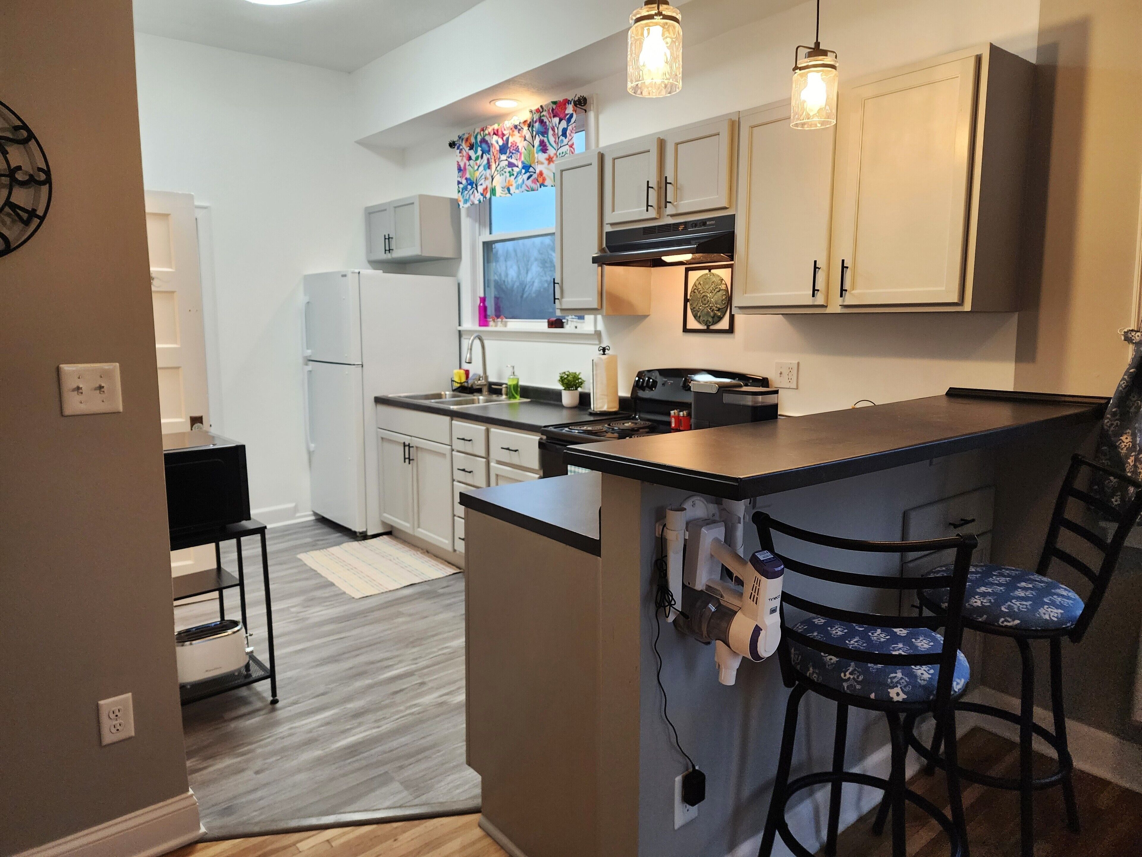 Una cocina moderna con una isla central, taburetes de bar e iluminación colgante.