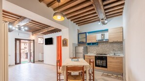 A spacious kitchen with wooden cabinets, a dining table, and a TV mounted on the wall. - Apartment 'La Porta Del Palio' with Private Terrace, Wi-Fi and Air Conditioning (Siena)