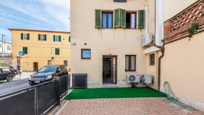 A building with a paved entrance, a green artificial turf, and a parked car. - Apartment 'La Porta Del Palio' with Private Terrace, Wi-Fi and Air Conditioning (Siena)