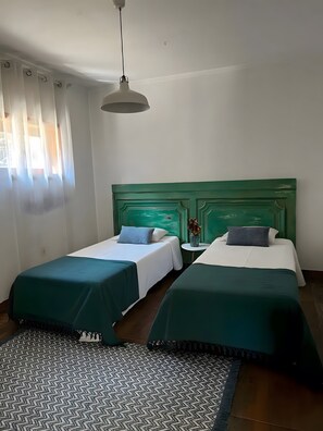A room with two beds, a patterned rug, a green headboard, and a hanging light fixture. - Holiday Home 'Casa Chocolate' with Mountain Views, Private Pool and Wi-Fi (Porto)