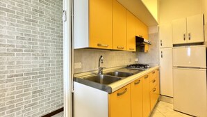 A kitchen with yellow cabinets, a stainless steel sink, and a white refrigerator.
