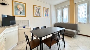 A modern kitchen with a dining table, chairs, a sofa, and artwork on the walls.