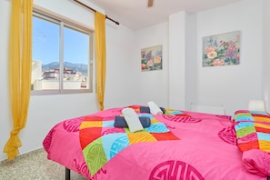 Un dormitorio con una cama grande, una ventana con cortinas y dos cuadros florales en la pared.