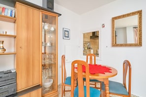 Ein Essbereich mit Holzschrank, Tisch und Stühlen sowie einem Spiegel an der Wand.