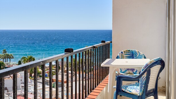 Un balcon avec vue sur l’océan, une table et une chaise.