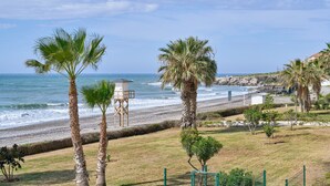 A beach view with palm trees, a lifeguard tower, and a grassy area. - Apartment 'Jardines Del Mar' with Sea Views, Private Terrace and Wi-Fi (Torrox)