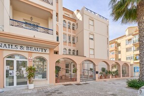 A building with a storefront labeled 'NAILS & BEAUTY' and a gated entrance with potted plants.