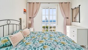 A bedroom with a bed, a nightstand, a dresser, and a view of the sea through a door. - Apartment 'Jardines Del Mar' with Sea Views, Private Terrace and Wi-Fi (Torrox)