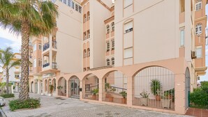 A multi-story hotel with balconies, a courtyard with potted plants, and a tiled pavement. - Apartment 'Jardines Del Mar' with Sea Views, Private Terrace and Wi-Fi (Torrox)