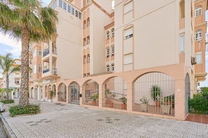 Un hôtel à plusieurs étages doté de balcons, d’une cour intérieure agrémentée de plantes en pot et d’un sol carrelé.