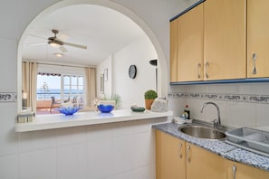 A kitchen with a white countertop, a sink, and wooden cabinets.