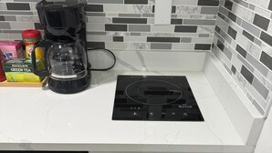 Eine Küche mit einer schwarzen Induktionskochplatte, einer Kaffeemaschine und einer Schublade voller Besteck.