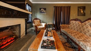 A cozy living room with a fireplace, a sofa, a chair, and a coffee table with magazines.
