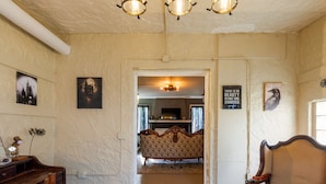 A room with a wooden ceiling, a vintage-style lamp, a treasure map rug, and a vintage sofa.