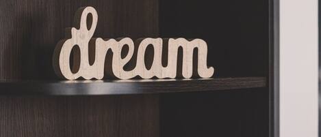 A wooden sign with the word "dream" on a dark wooden shelf.