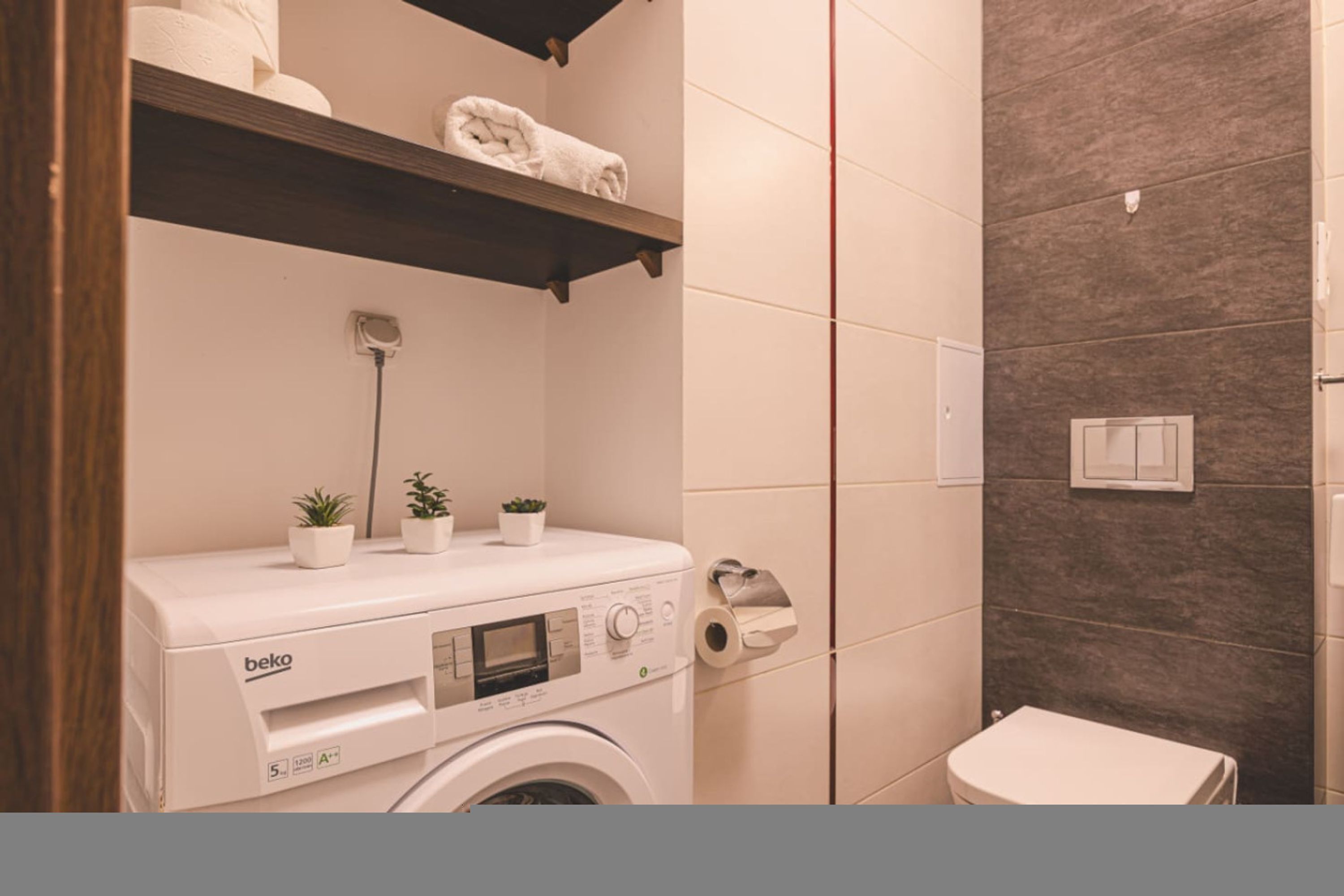 Ein kleines Badezimmer mit Waschmaschine, Toilette und Ablagefläche für Handtücher.