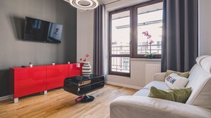 A modern living room with a red cabinet, a black coffee table, a white sofa, and a large window with curtains. - Dream 14 Przytulne Studio Centrum Bydgoszczy (Bydgoszcz)