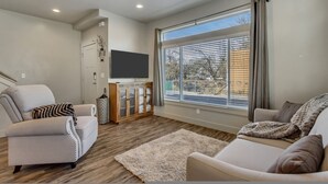 A modern living room with a sofa, armchair, and a flat-screen TV on a wooden cabinet. - Hill Field 2 by CDH in Layton (Layton)
