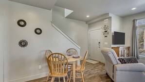 A dining area with a wooden table and chairs, a sofa, and a staircase leading to another room. - Hill Field 2 by CDH in Layton (Layton)