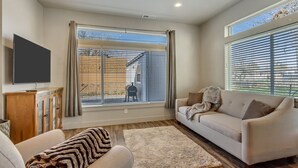 A living room with a sofa, a television, and a large window with blinds. - Hill Field 2 by CDH in Layton (Layton)