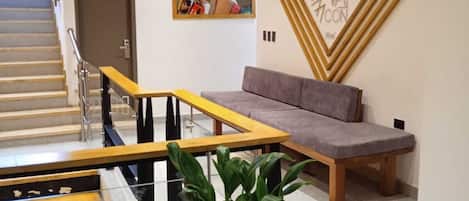 Un moderno vestíbulo de hotel con una escalera, un área de descanso y un elemento decorativo en la pared.