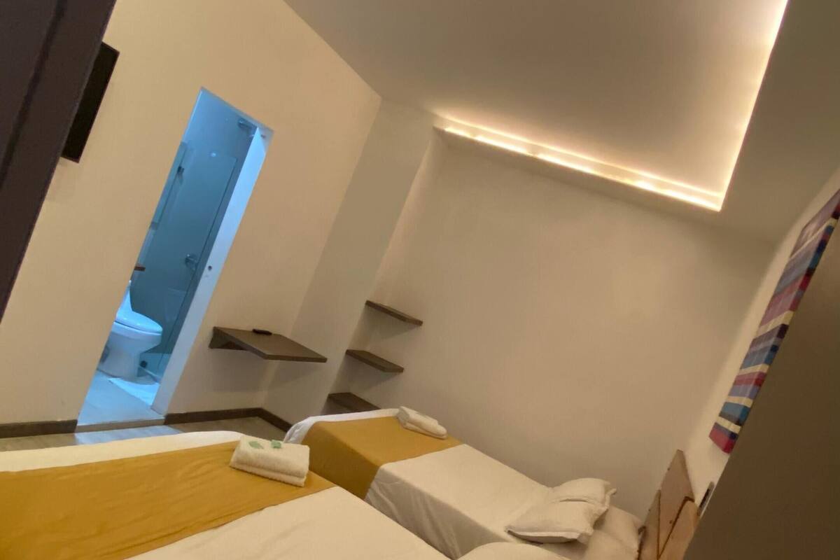 Una habitación de hotel moderna con una cama grande, un escritorio pequeño y un baño visible a través de una puerta abierta.