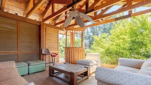 A covered outdoor seating area with wooden furniture, a ceiling fan, and a view of greenery. - Wonderful large family cottage (Curacavi-Lolenco)