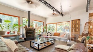 A spacious living room with a fireplace, leather sofas, a glass coffee table, and large windows offering a view of greenery. - Wonderful large family cottage (Curacavi-Lolenco)