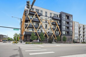A modern building with a distinctive geometric facade, a visible street sign, and a crosswalk. - Golden Hour | 1BR LoHi Loft | Balcony | Dog-Friendly (Denver)