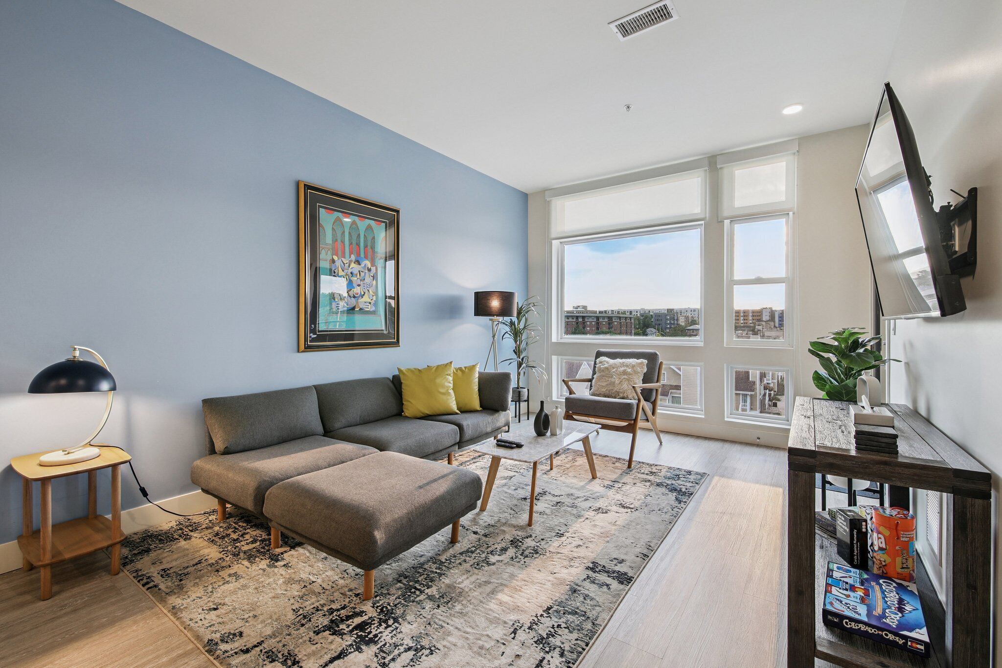 A modern living room with a grey sofa, a coffee table, and a bookshelf.