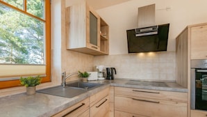 A modern kitchen with wooden cabinets, a stainless steel sink, and a built-in oven.