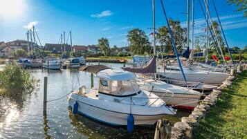 Un port de plaisance où des bateaux sont amarrés le long d’une berge herbeuse.