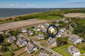 Vista aerea di una zona residenziale con case, una distesa d'acqua e un'icona a forma di cuore che indica una posizione.