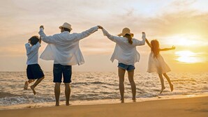 A family of four at the beach during sunset.