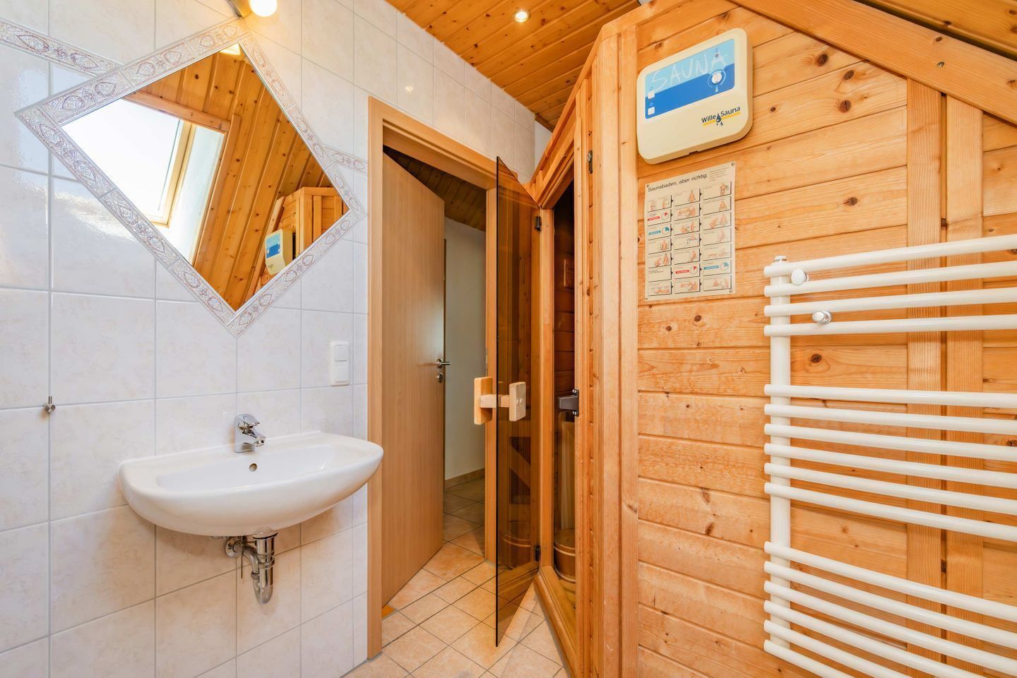 A bathroom with a sink, mirror, and sauna sign.