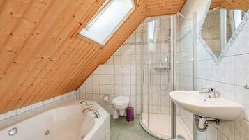 Une salle de bain avec un plafond en bois, une baignoire, une douche, des toilettes et un lavabo.